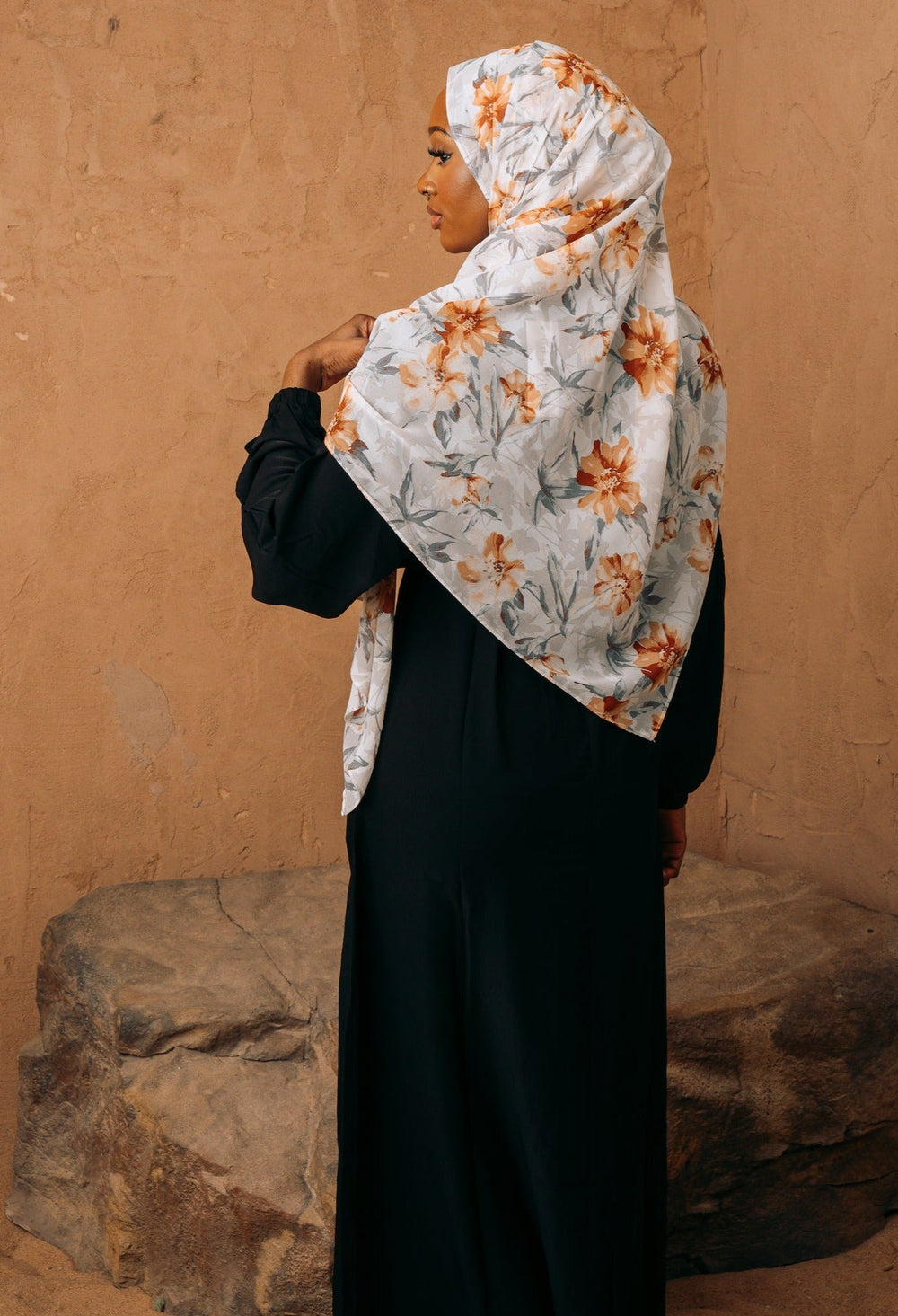 a woman in a hijab standing in front of a wall