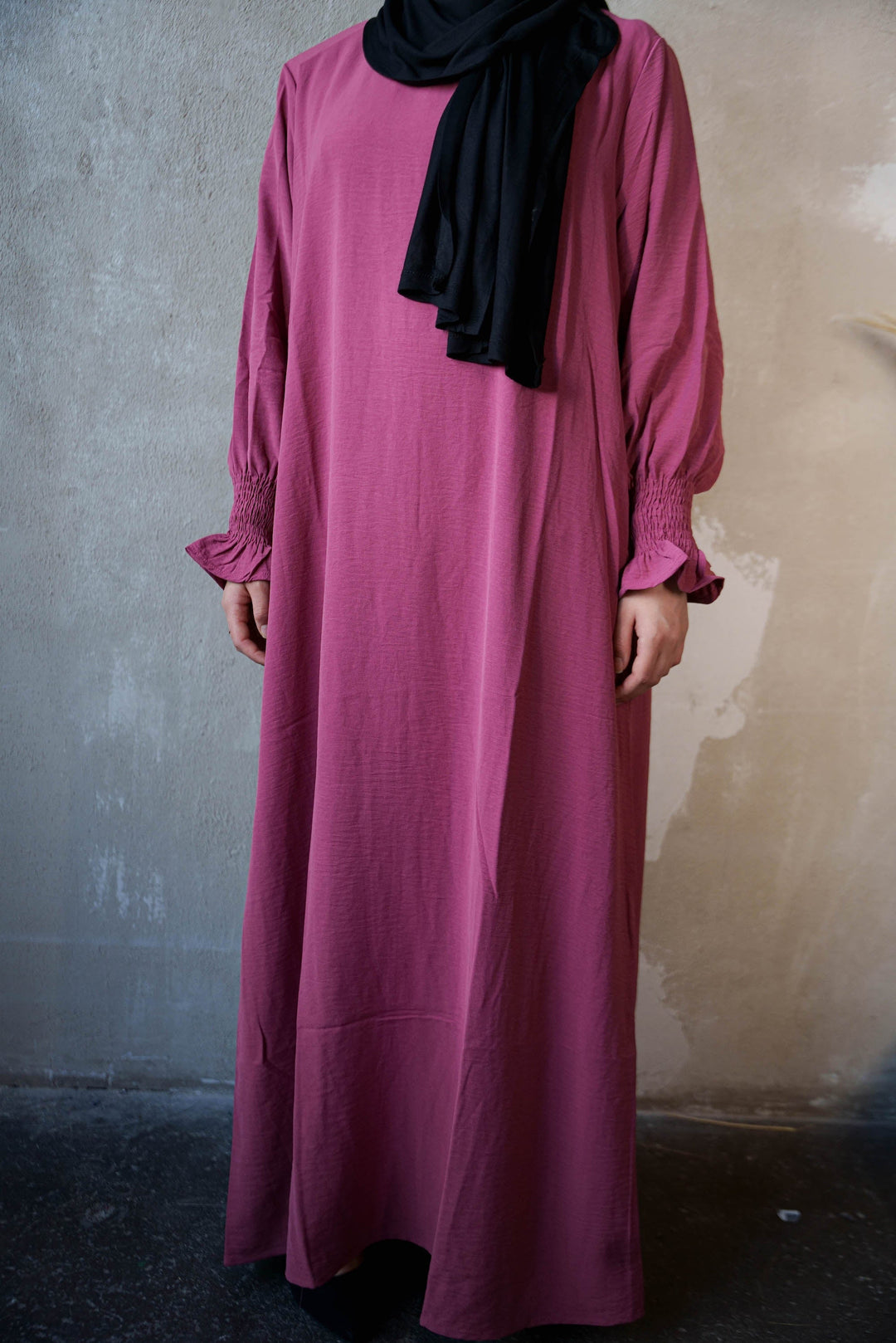 a woman wearing a pink dress and a black scarf