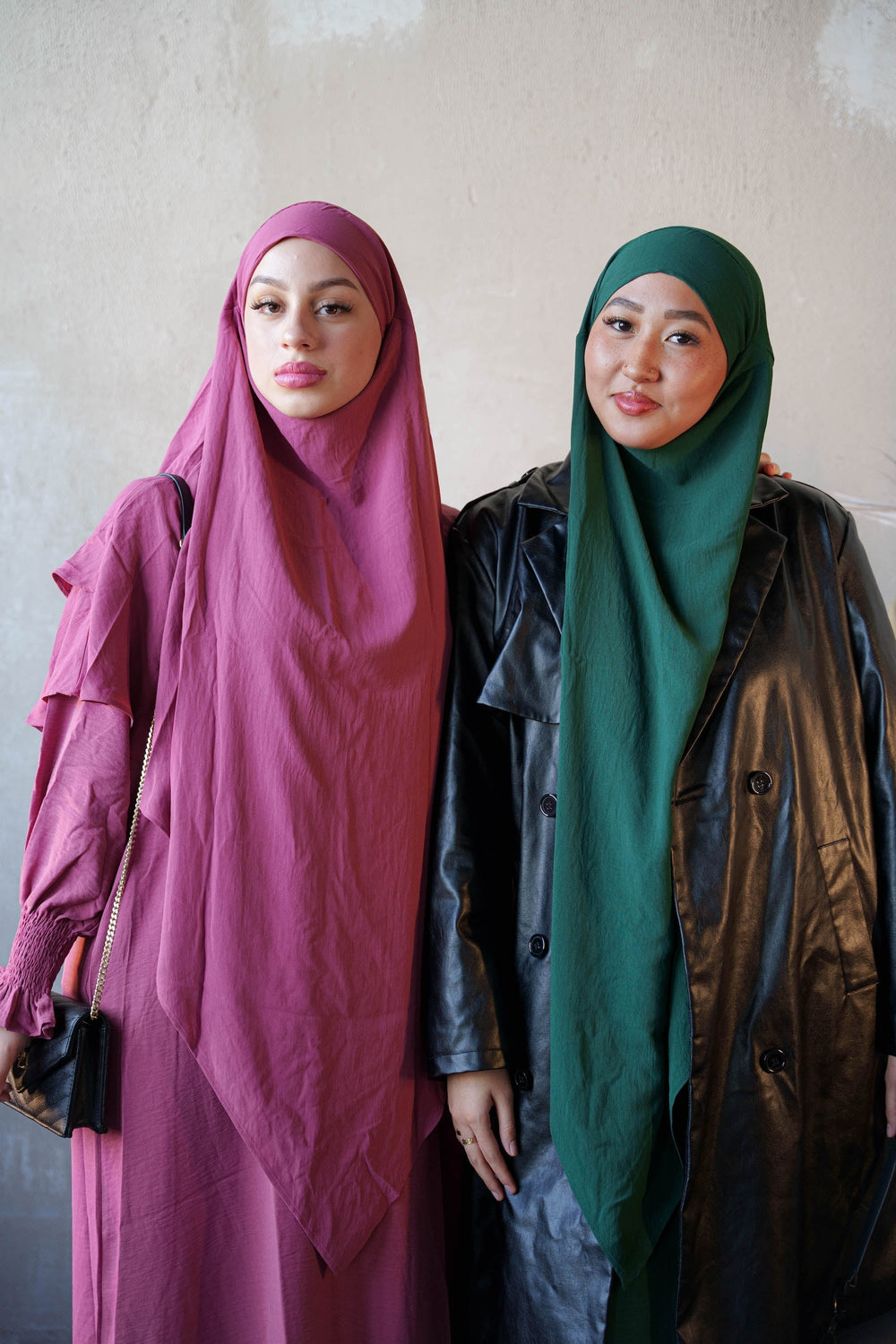 two women standing next to each other wearing headscarves
