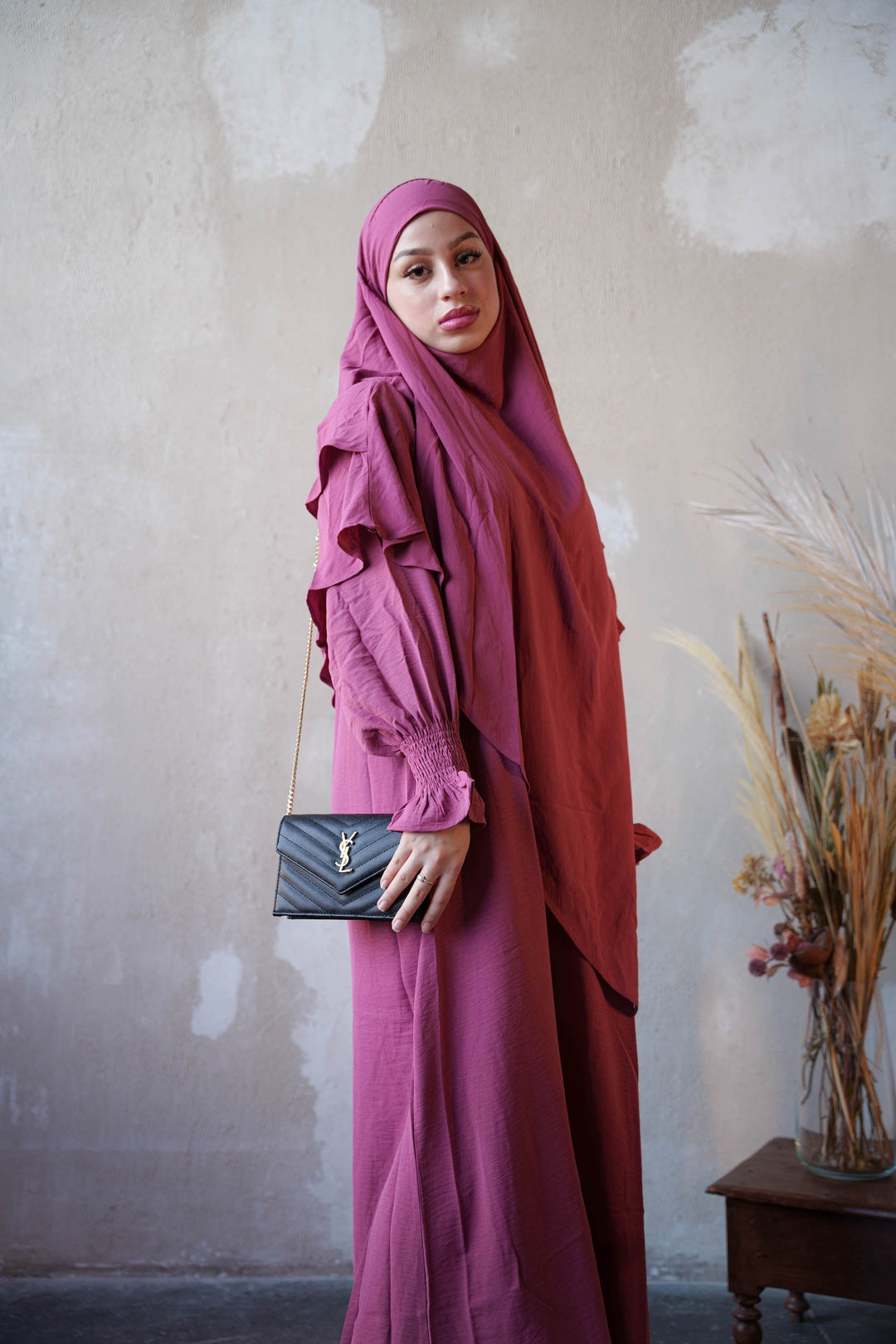 a woman in a hijab is holding a purse