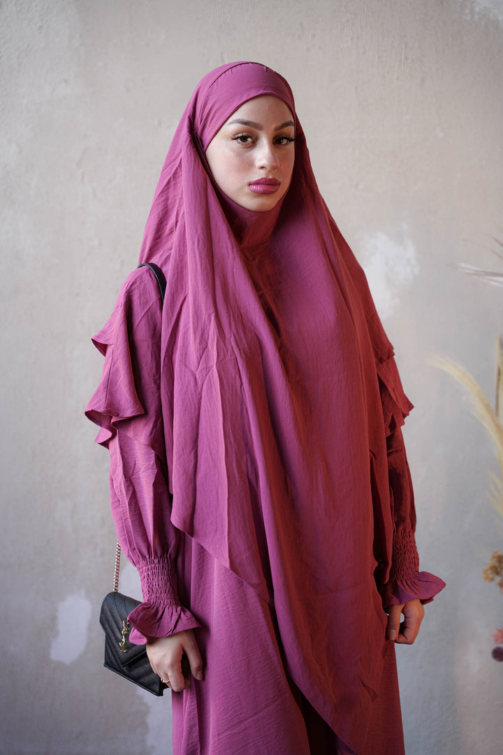 a woman in a purple hijab poses for a picture
