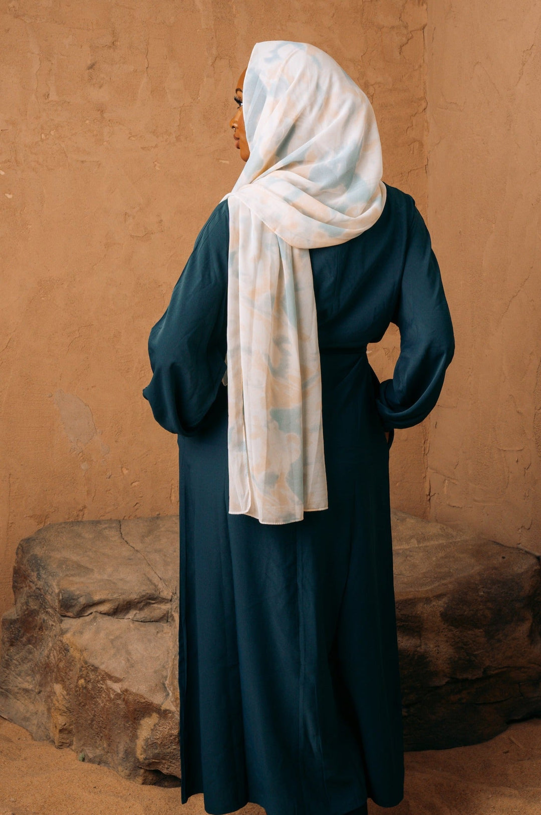 a woman wearing a blue dress and a white scarf