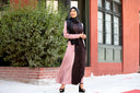 Woman wearing a stylish pink abaya and black hijab outside, featuring long sleeves and detailed patterns. Clearance sale on modest fashion.