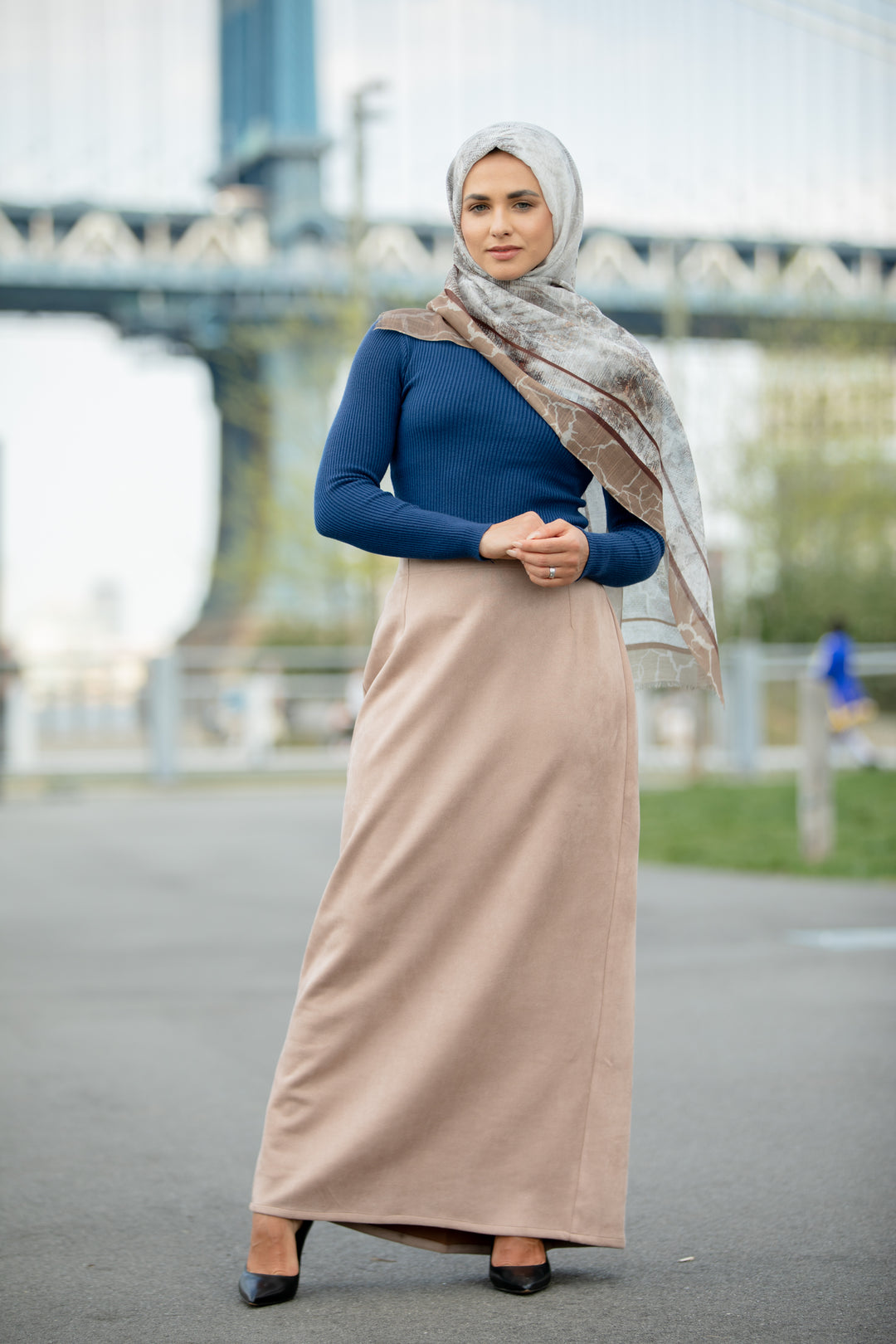 Woman wearing Sand Suede Pencil Maxi Skirt with blue top and headscarf near an urban bridge background