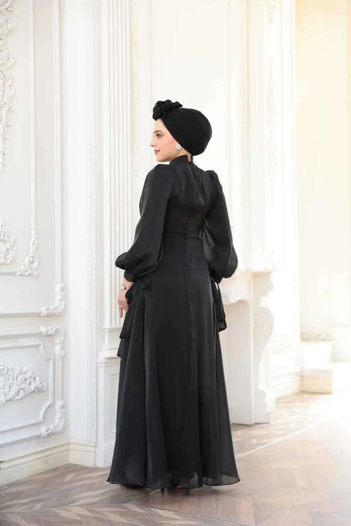 Woman in Black Organza Criss Cross Gown standing in elegant room with white decor.
