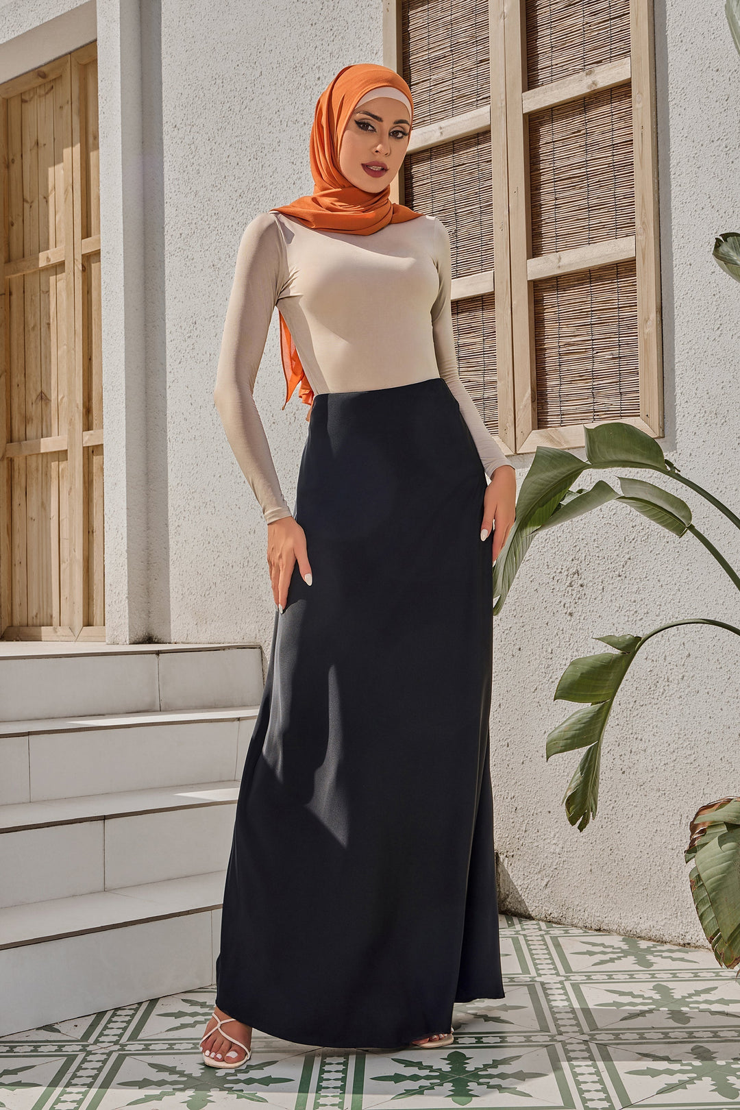 Woman in orange hijab wearing black satin maxi skirt