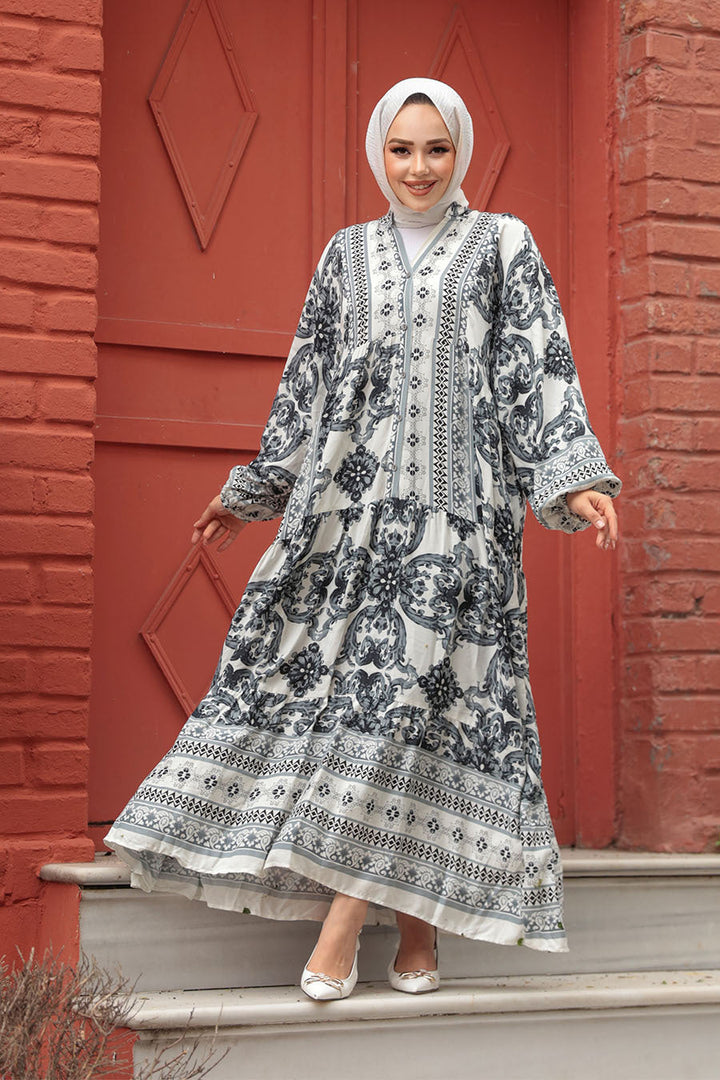 Woman in flowy patterned maxi dress in front of red brick building.
