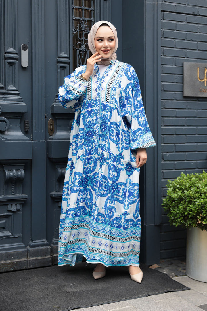 Blue and white long-sleeve maxi dress with floral pattern, worn by a model standing outside a stylish blue door.