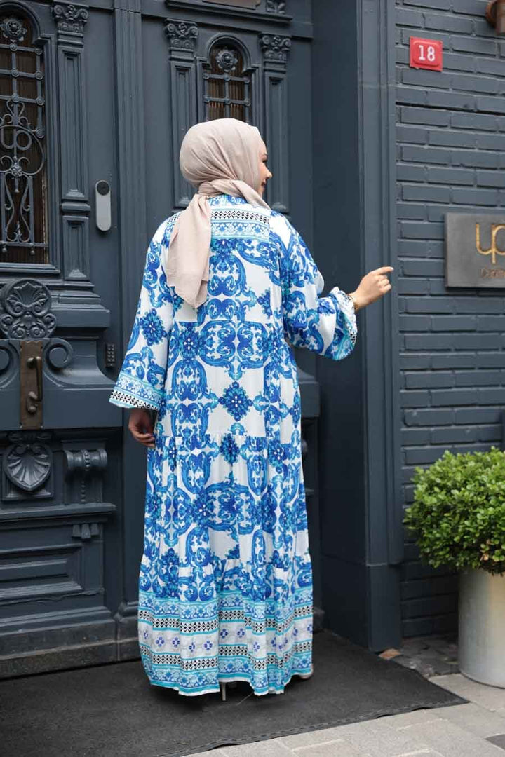 Person wearing Blue Tropical Smocked Maxi Dress CLEARANCE standing outdoors near a vintage blue door.