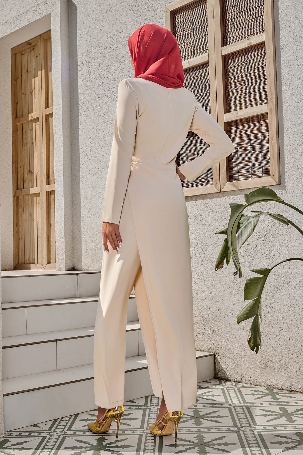 Woman in cream side knot jumpsuit and red hijab