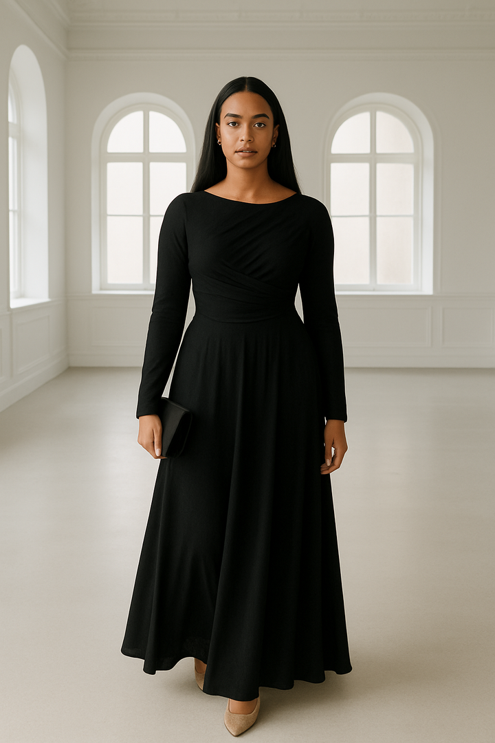 Woman in elegant black drop waist dress standing in a bright room