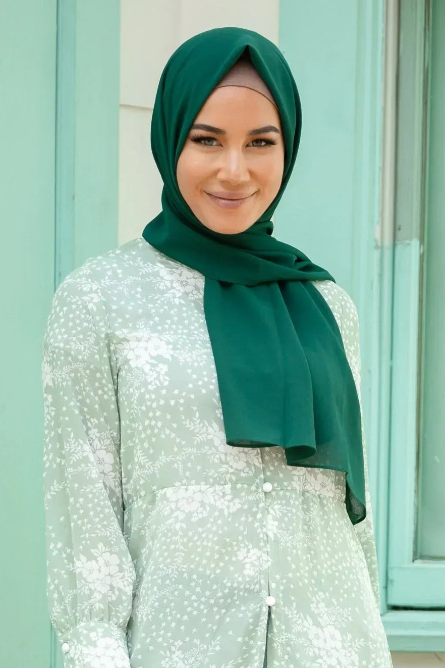 Woman wearing Forest Green Chiffon Hijab, styled elegantly with a light green floral dress.