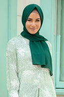 Woman wearing Forest Green Chiffon Hijab, styled elegantly with a light green floral dress.