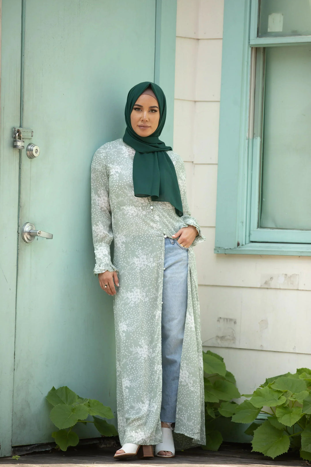 Woman wearing Forest Green Chiffon Hijab in stylish outfit against green door backdrop