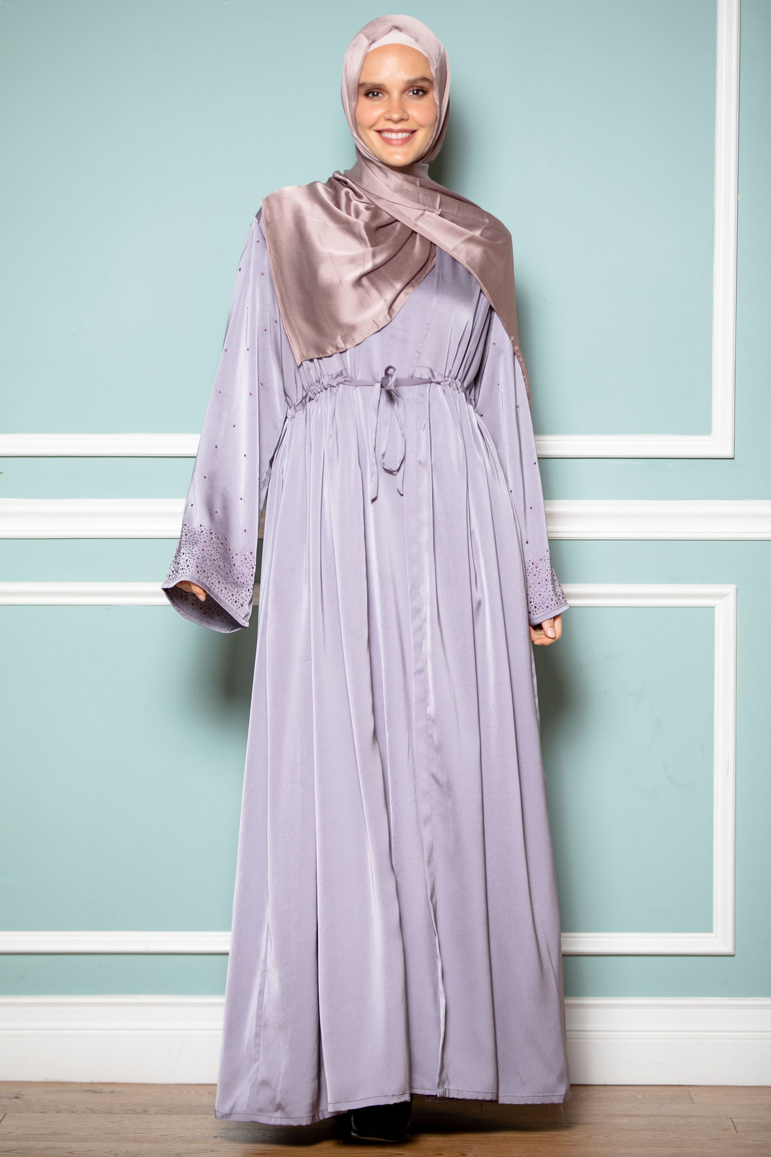 Woman in lilac dress and headscarf wearing gray satin drawstring open front abaya