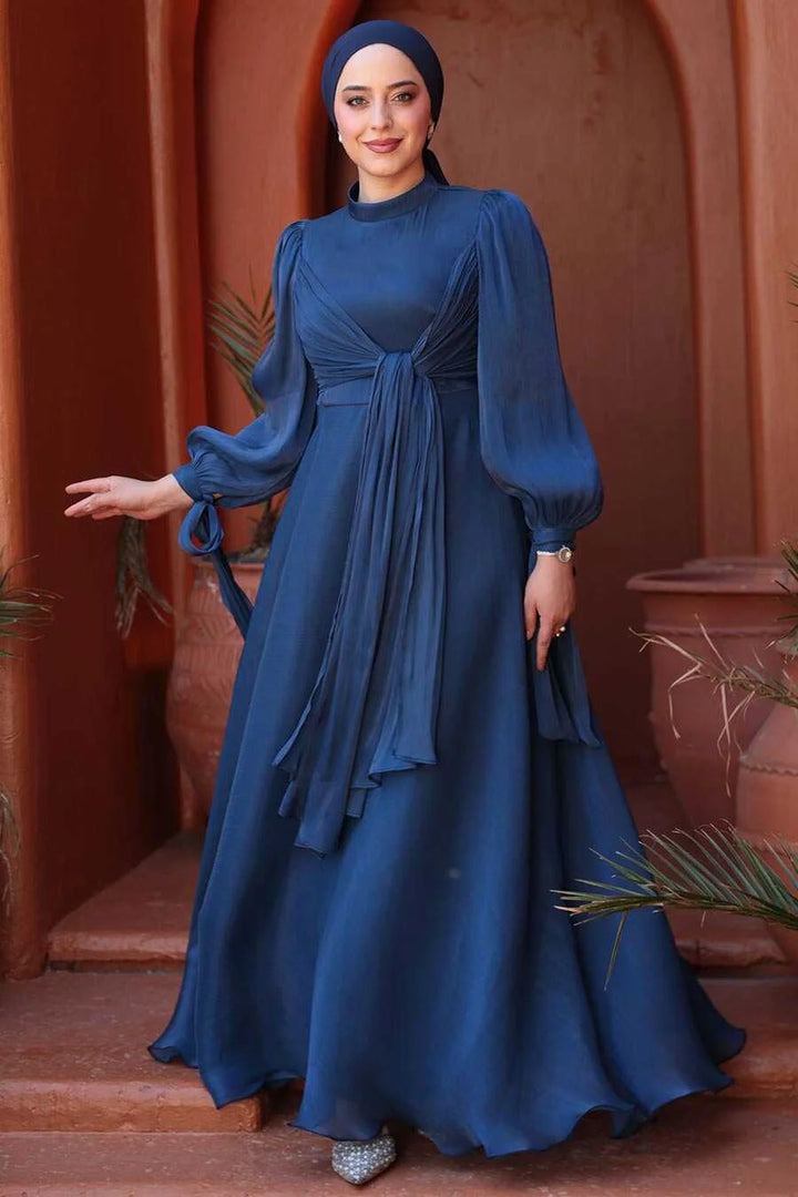 Woman wearing Navy Blue Organza Criss Cross Gown with fit and flare design, urban setting.