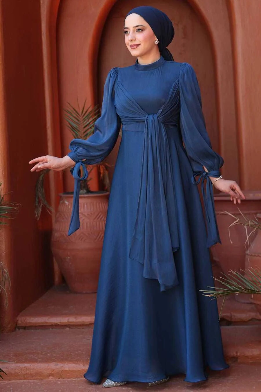 Woman wearing Navy Blue Organza Criss Cross Gown with long sleeves and flowing fit.