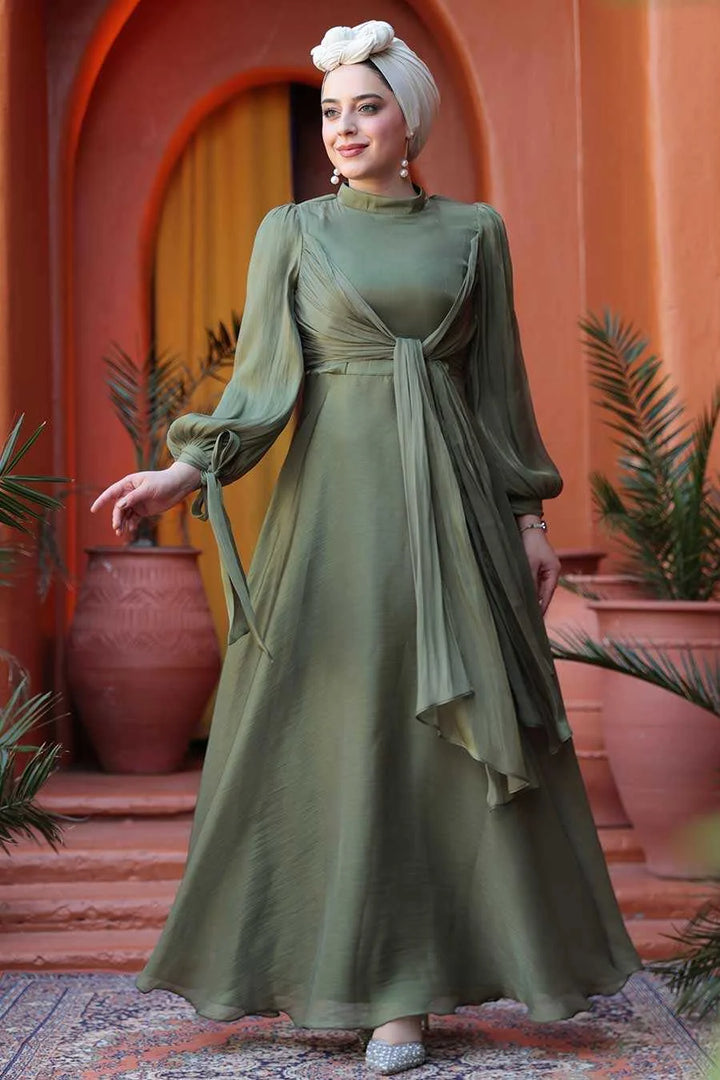 Model wearing Olive Green Organza Criss Cross Gown with fit and flare silhouette in elegant setting.