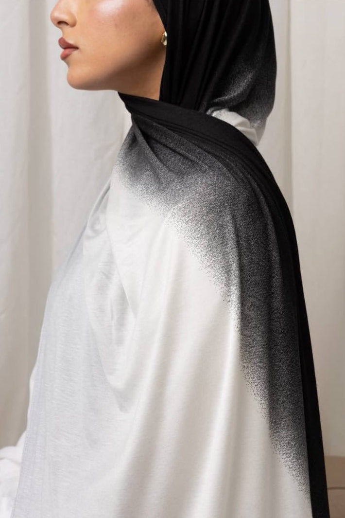 Side profile of woman wearing Ombré Jersey Hijab in black and white, showcasing its lightweight draping and elegant design.