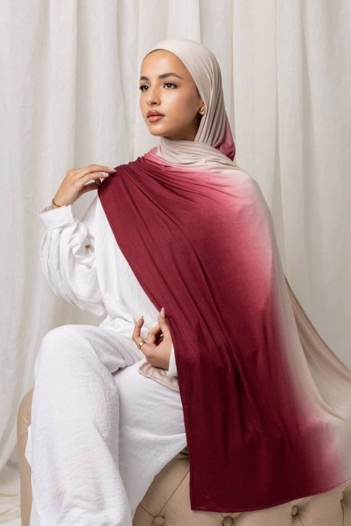 Woman wearing an Ombré Jersey Hijab, lightweight and easy to drape, in a stylish red to beige gradient. Perfect for any occasion.