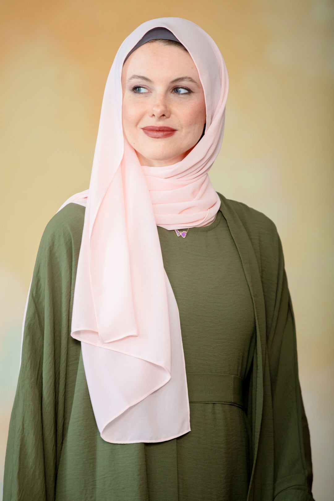 Woman in hijab and olive green dress wearing Peach Chiffon Hijab