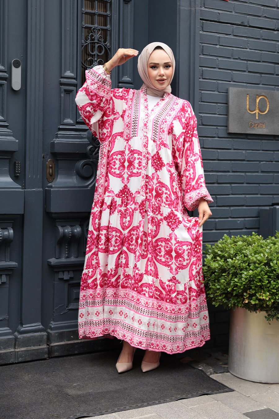 Model wearing Pink Tropical Smocked Maxi Dress-CLEARANCE with elastic cuffs and ruffle hem, outdoor urban background.