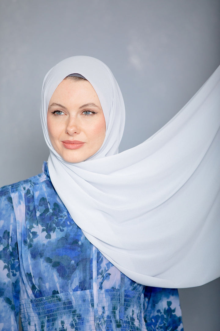 Woman in white chiffon hijab and blue patterned dress