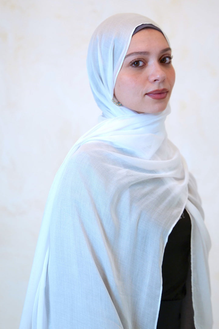 Woman wearing a white fringe edge modal hijab made from eco-friendly TENCEL™ fibers, showcasing opaque, ultra-soft material and stylish design.