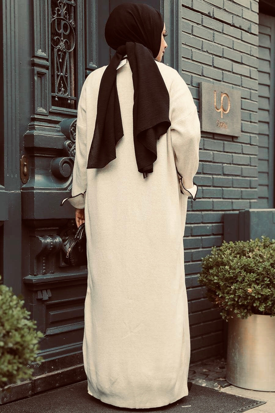 Woman in a long beige sweater dress abaya set wearing a black hijab