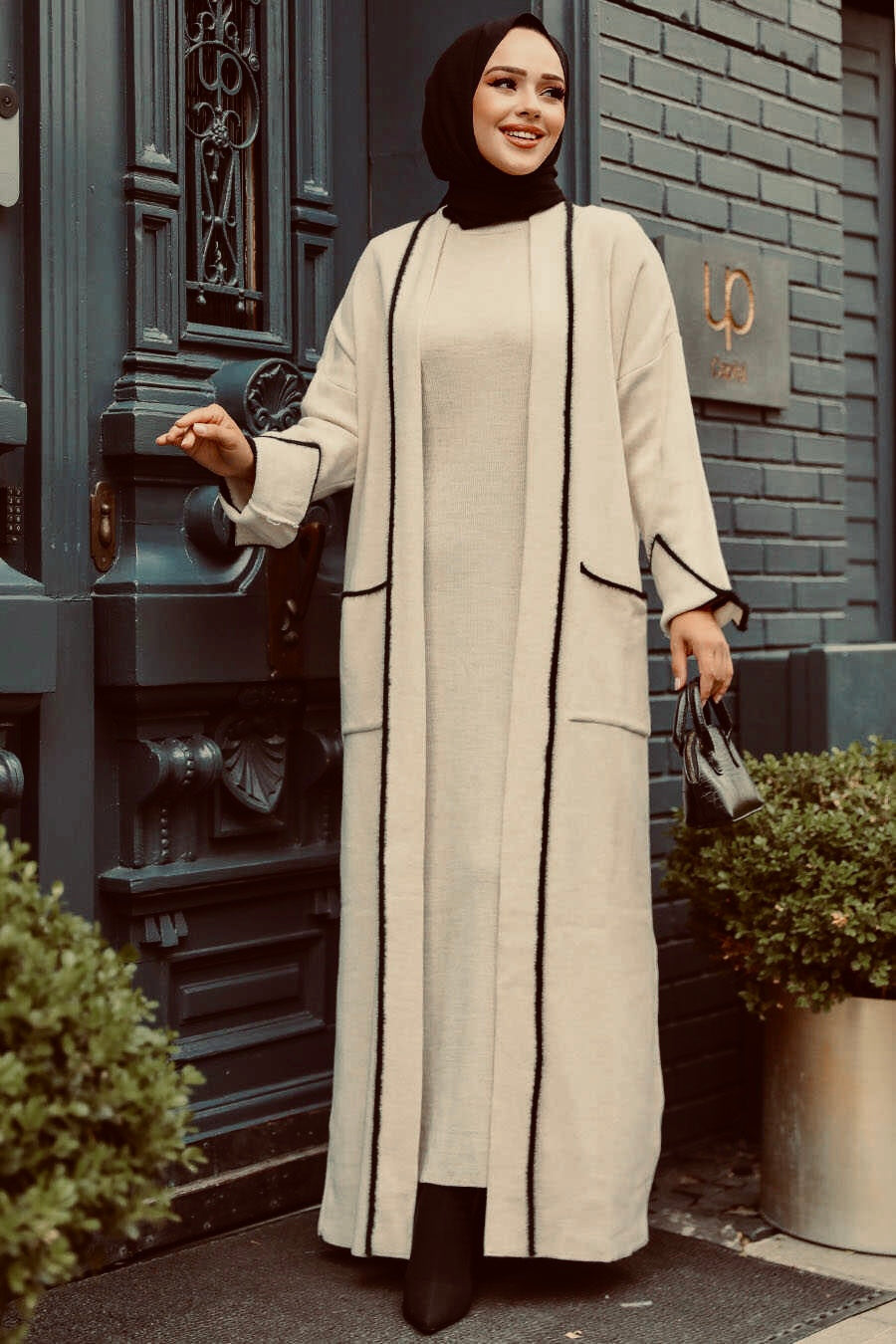 Woman in a cream dress abaya set with black trim featuring a beige sweater dress