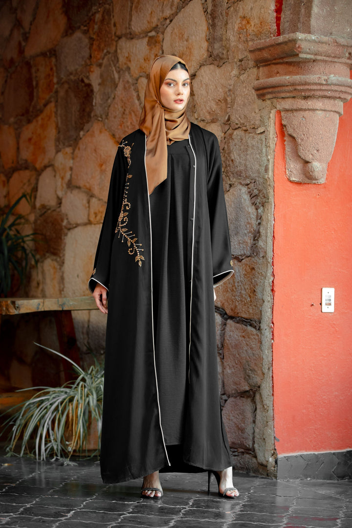 Elegant black abaya with gold embroidery and beaded button details for a sophisticated look