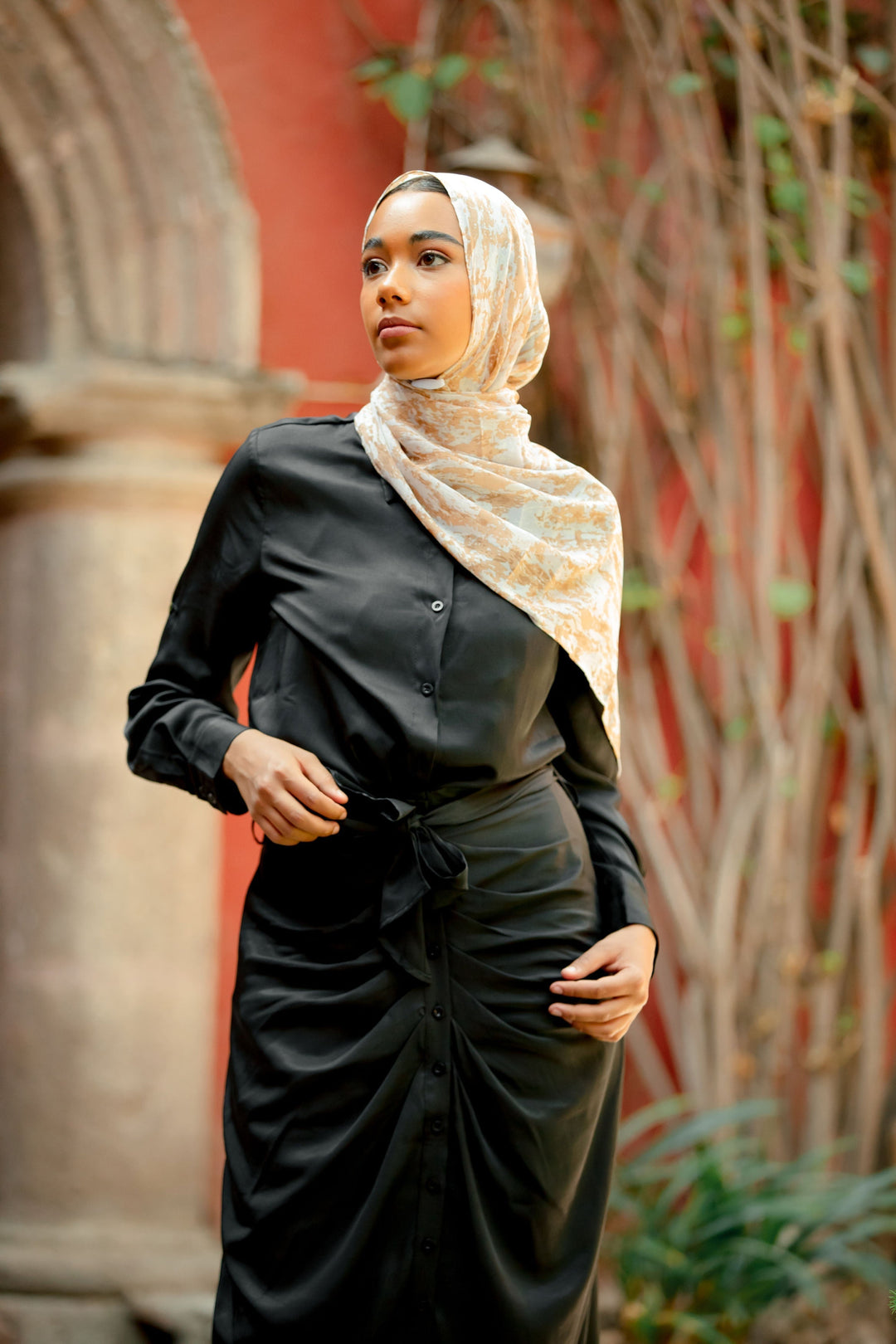 Woman in black satin dress and patterned hijab wearing a stylish black button skirt set