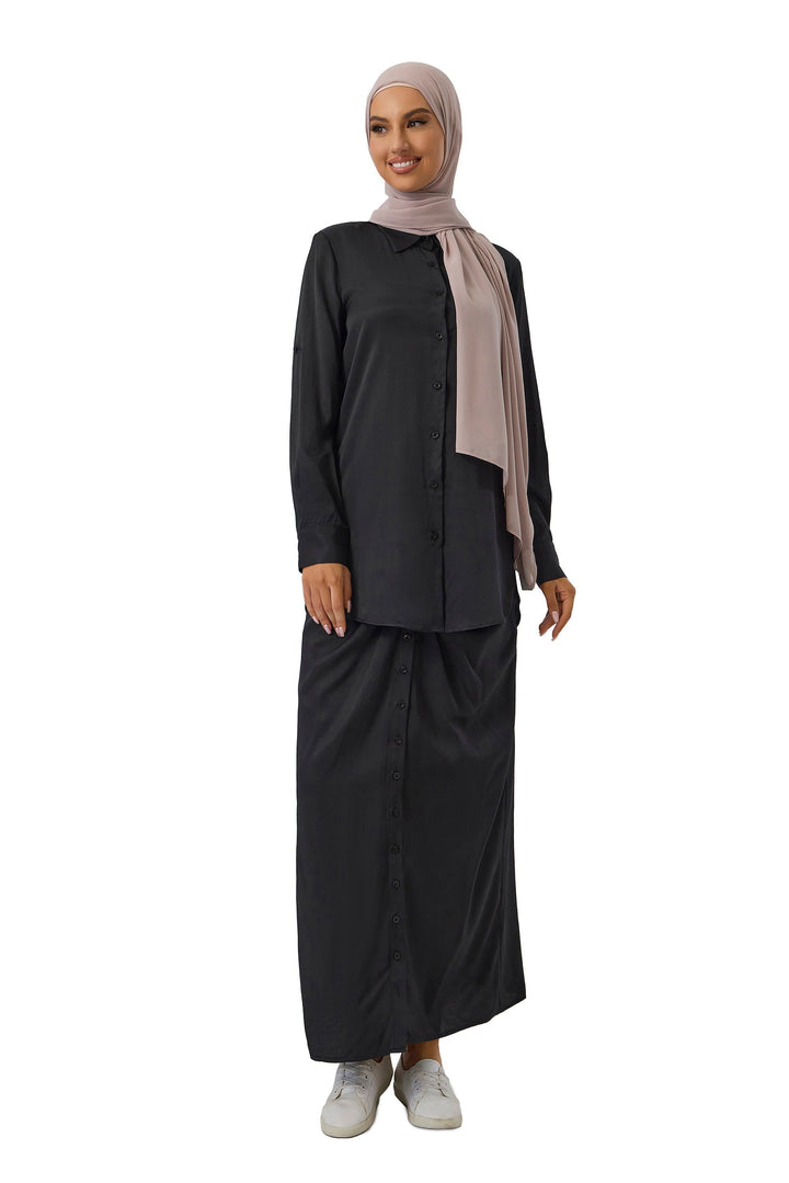 Woman in black modest sportswear with hijab wearing a black button shirt and skirt set