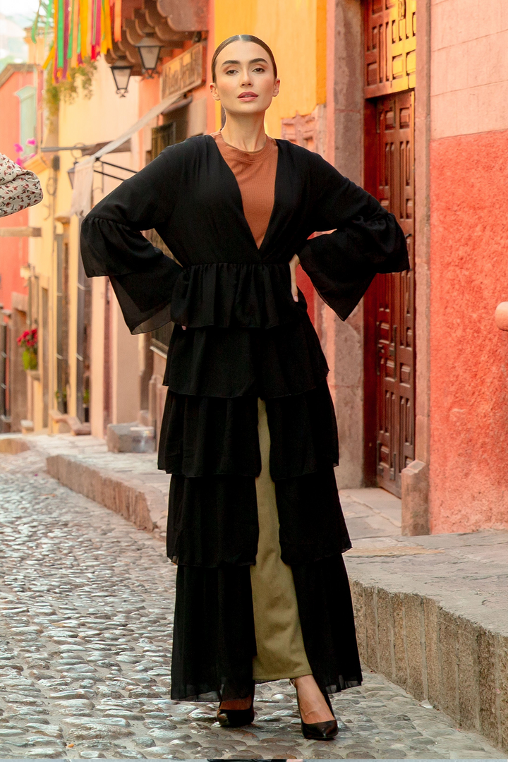 Woman in a black cascading ruffles open front abaya featuring tiered ruffles