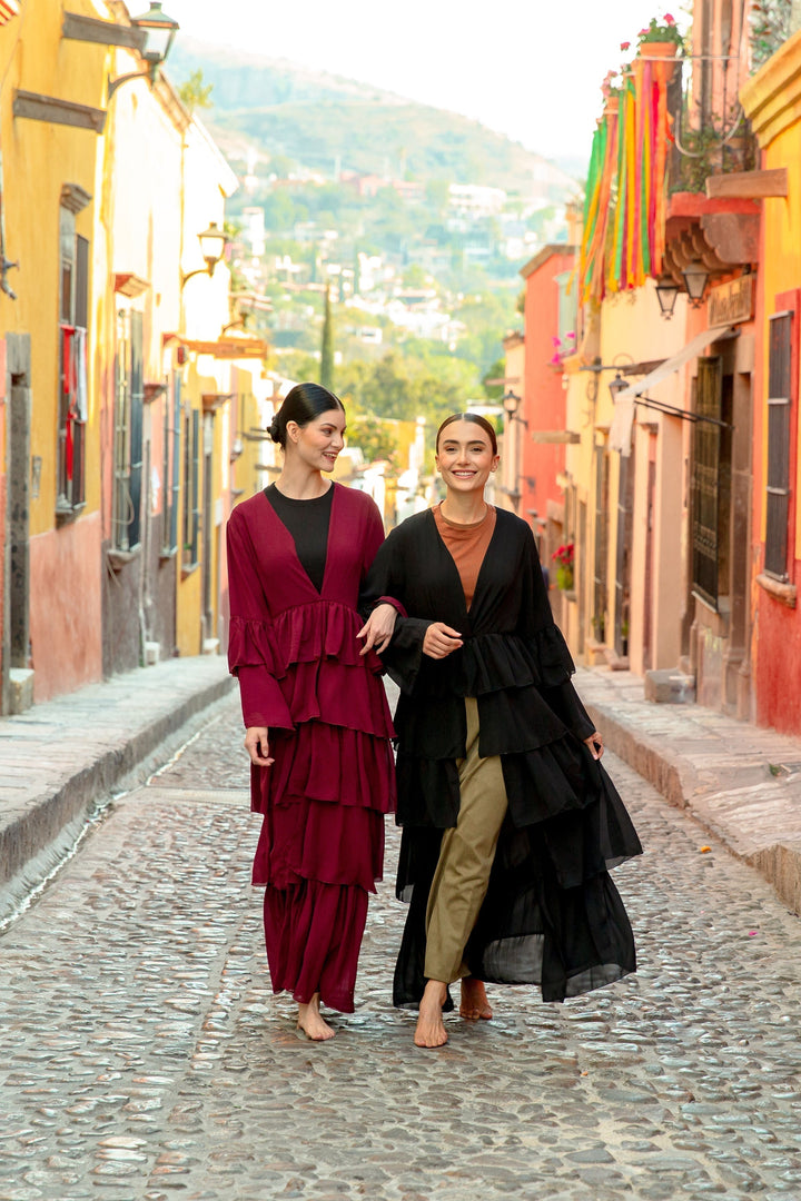 Two women in layered outfits showcasing the Black Cascading Ruffles Open Front Abaya