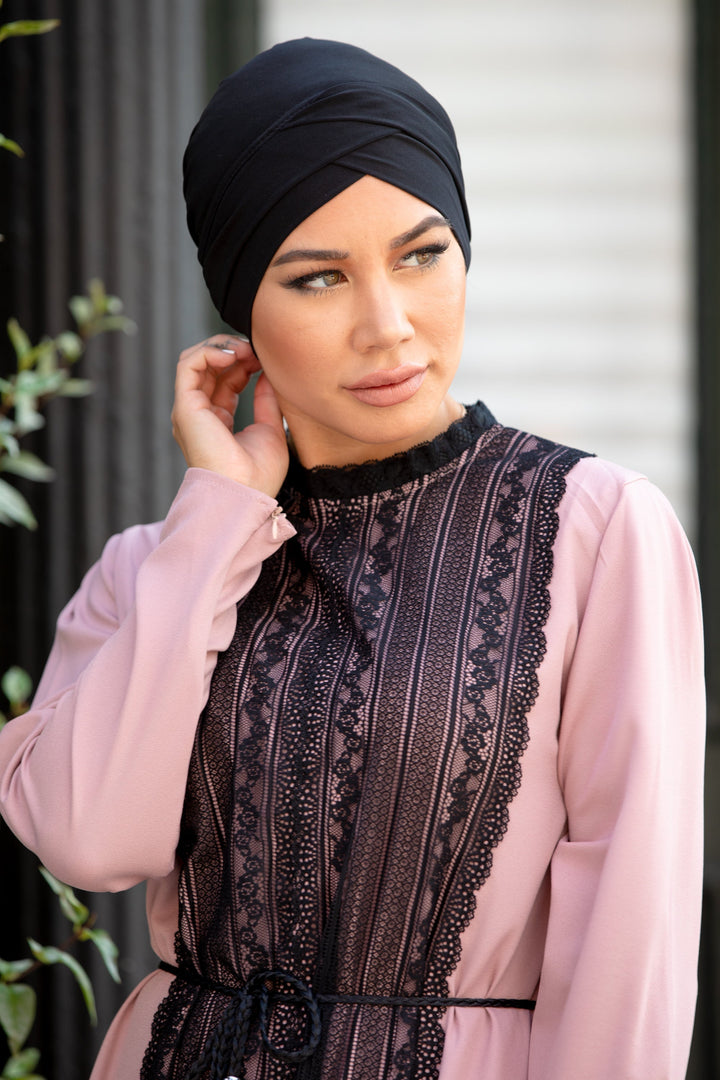 Woman in pink dress wearing a black criss cross cap hijab underscarf with lace details