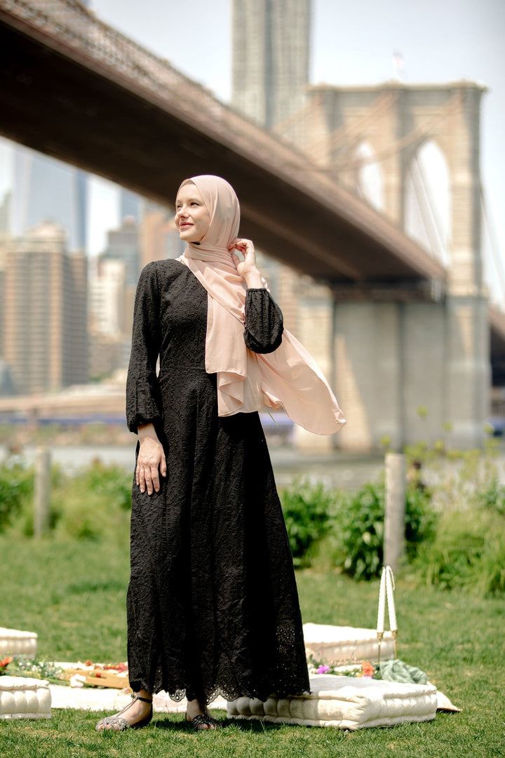 Elegant black eyelet long sleeve maxi dress paired with a peach hijab for chic style