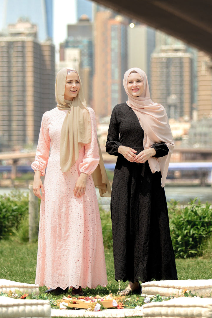 Two women in modest black eyelet long sleeve maxi dresses and hijabs