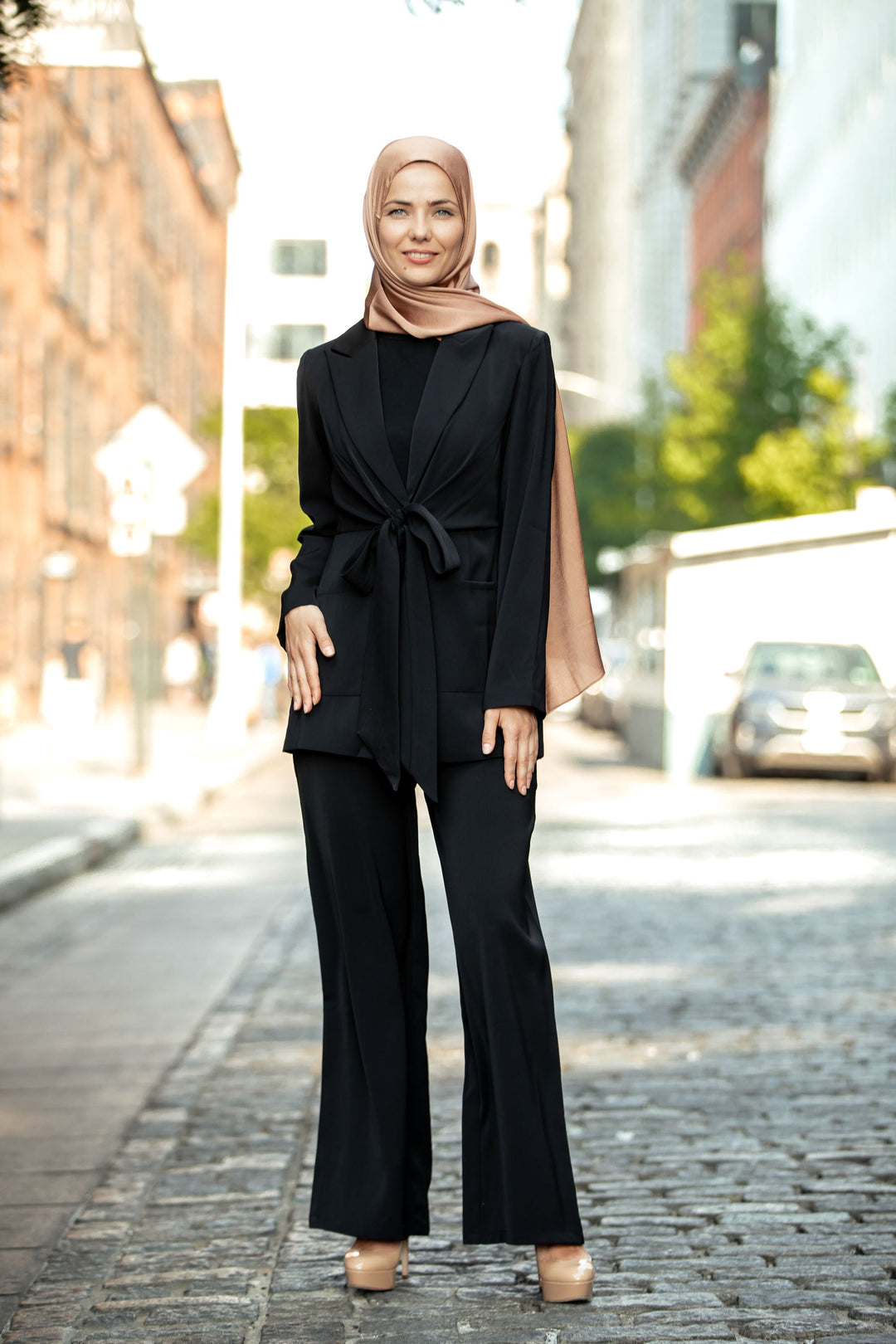 Woman in black pantsuit and hijab featuring a stylish black jacket and tailored look