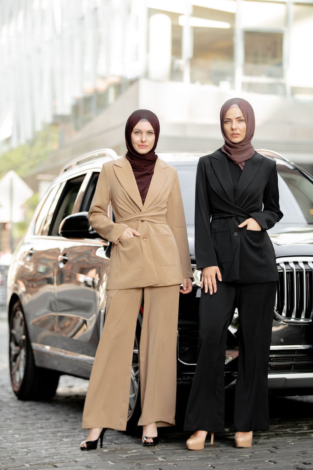 Two women in business attire featuring a stylish black jacket and pants suit set