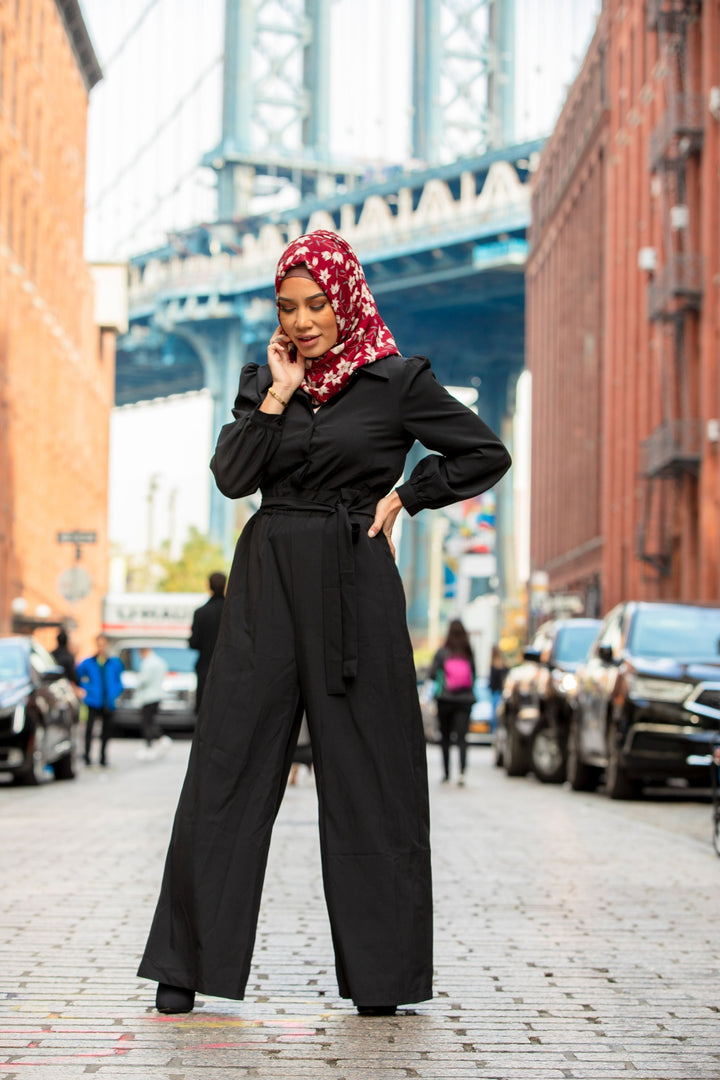 Woman in a black jumpsuit and floral hijab modeling the Black Lattice Jumpsuit