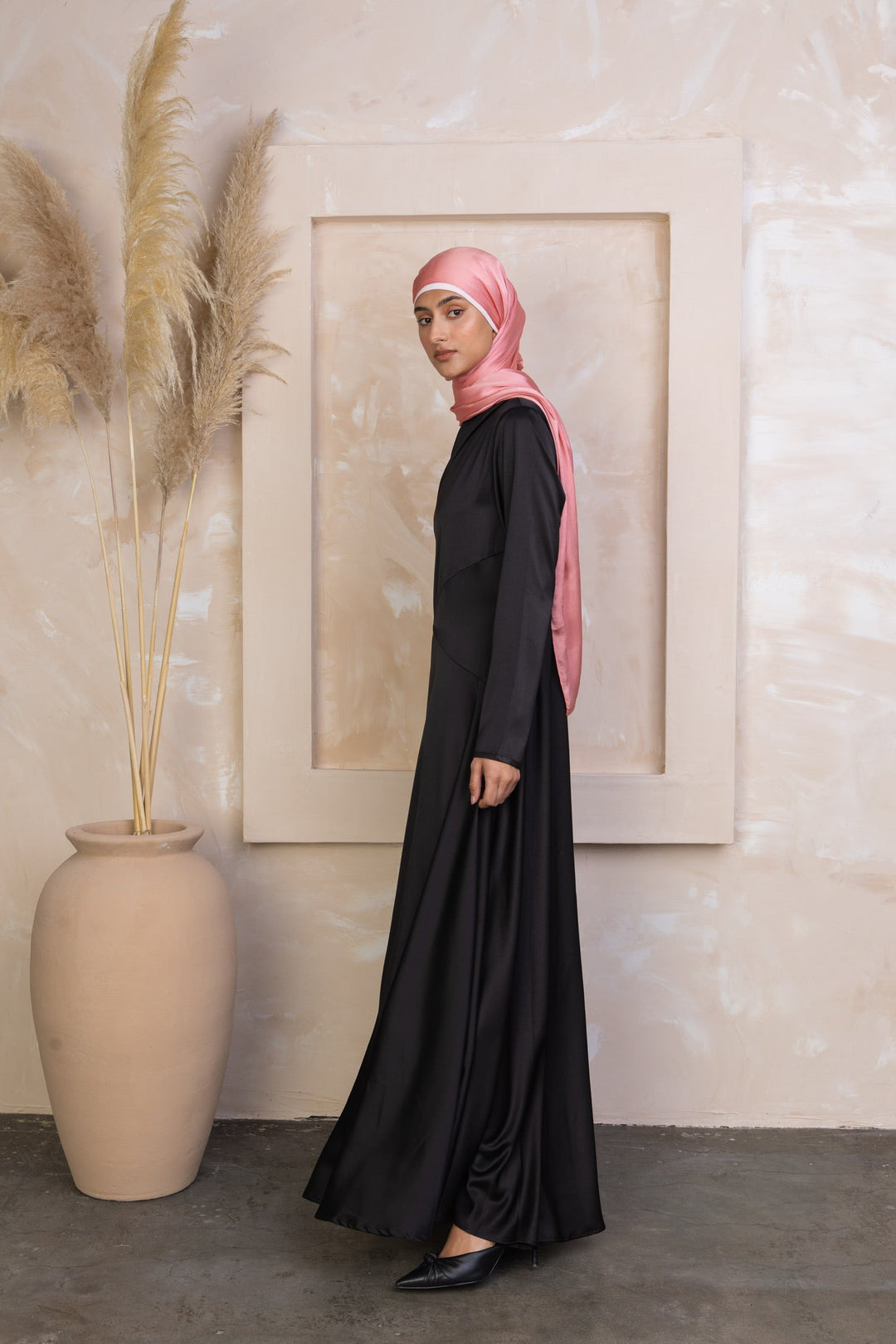 Woman in black satin shoulder cape long sleeve gown with pink hijab on clearance