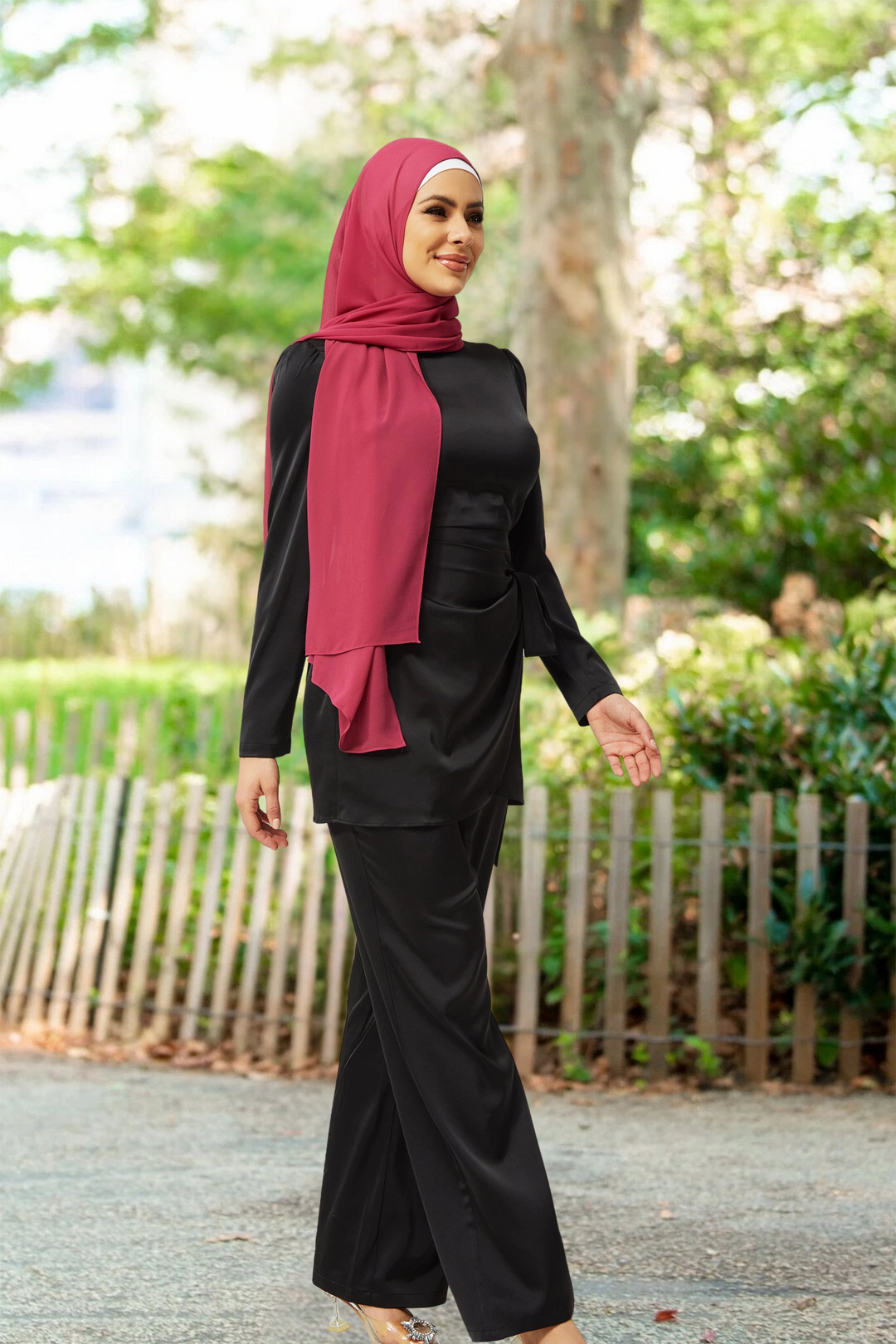 Woman in black wrap tunic and pant set, featuring a stylish red hijab