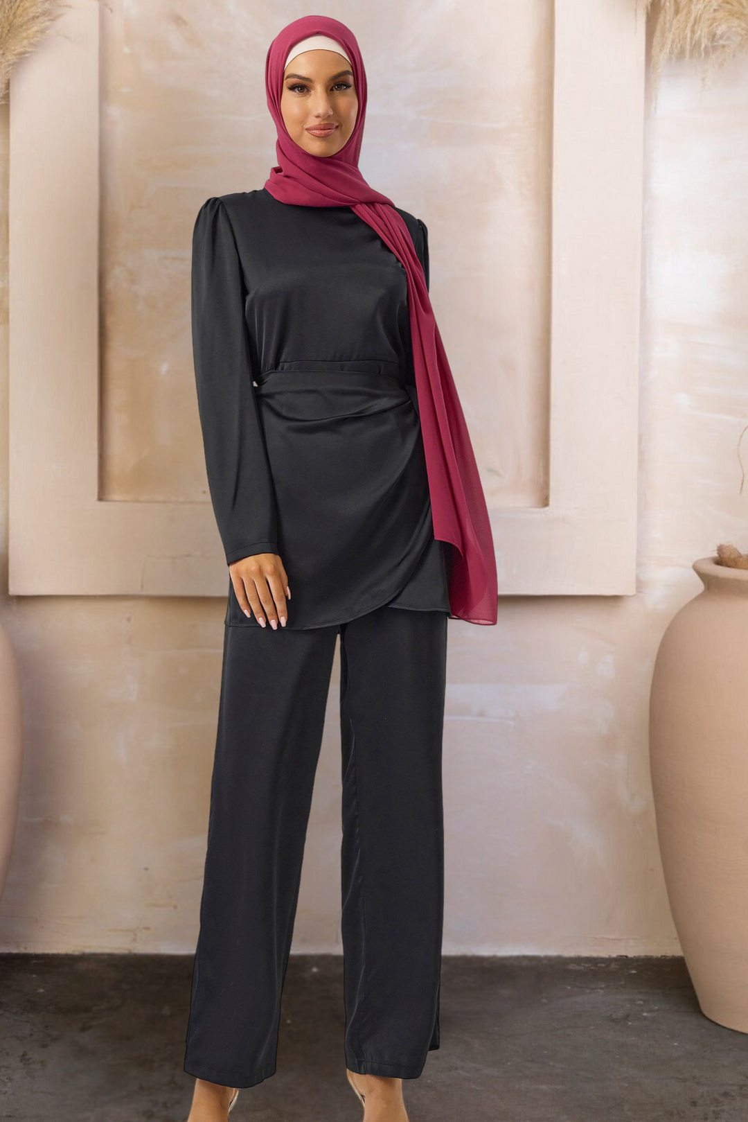 Woman in black satin side wrap tunic and pant set with red hijab in modest fashion