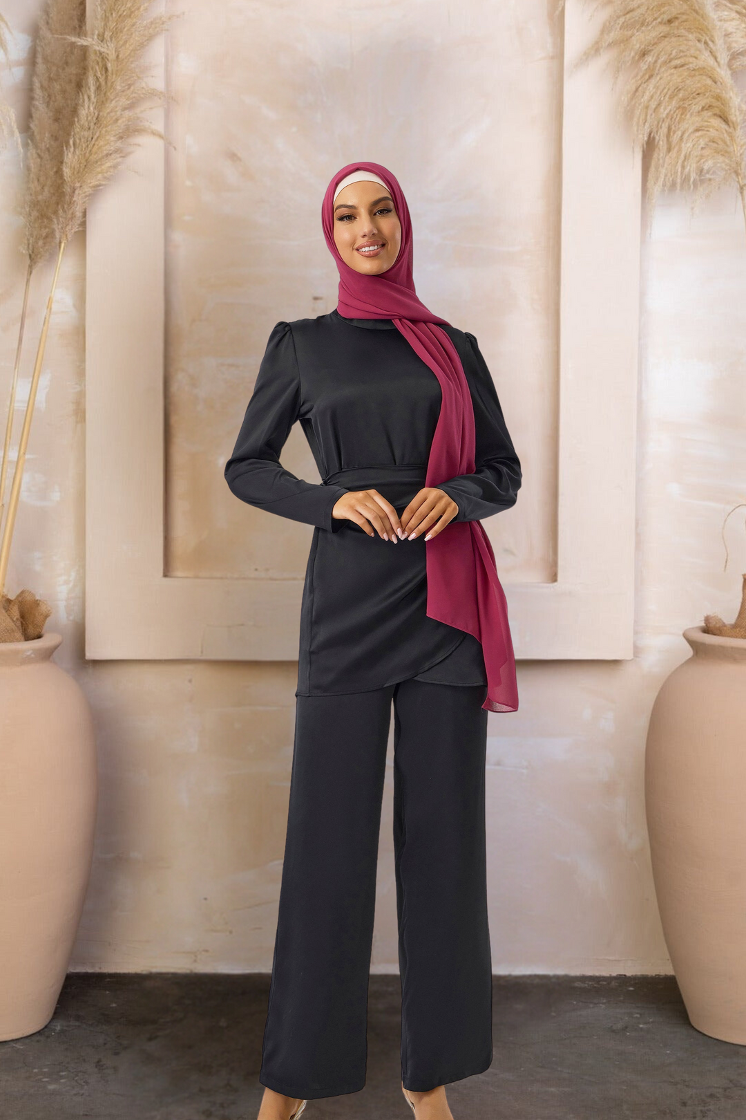 Woman wearing a black satin wrap tunic and pant set with a maroon hijab