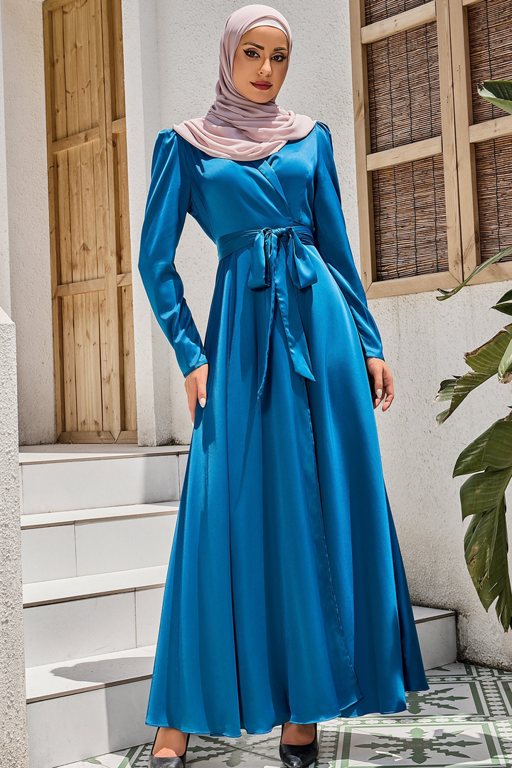 Woman in a long-sleeved blue criss cross tie maxi dress showcasing stylish elegance