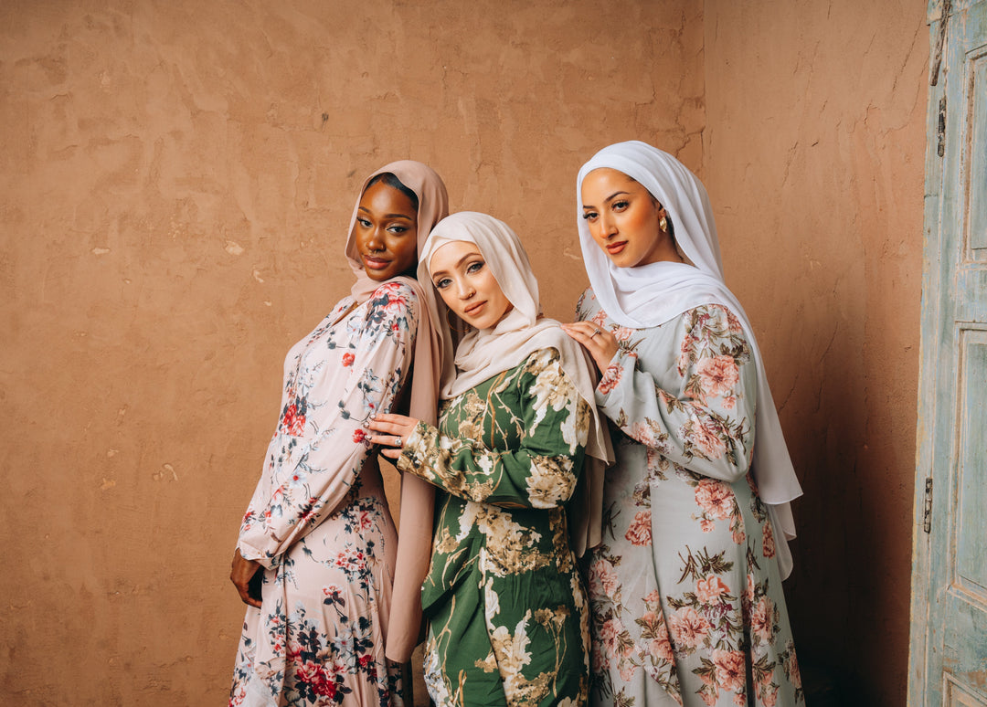 Three women in blush pink ruffle dresses and hijabs enjoying a stylish moment