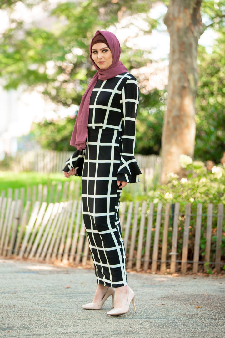 Black and white grid-patterned dress with ruffle sleeves paired with brown criss-cross underscarf