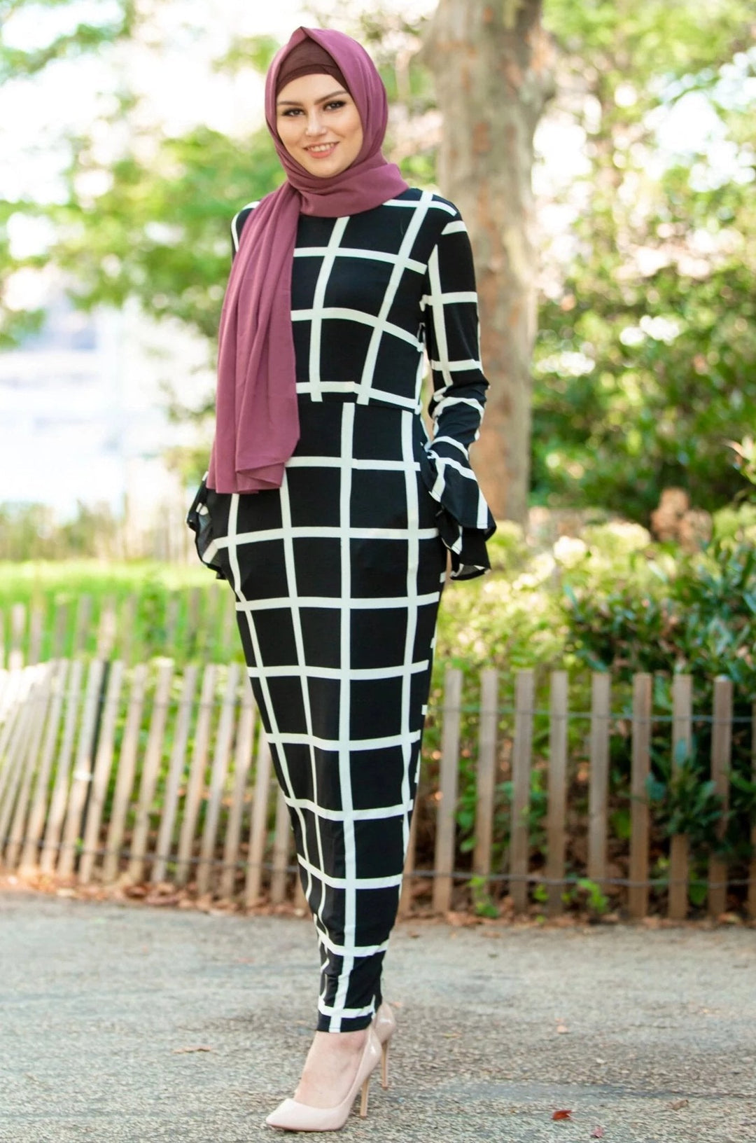 Woman in black and white grid dress with maroon hijab and brown criss-cross underscarf