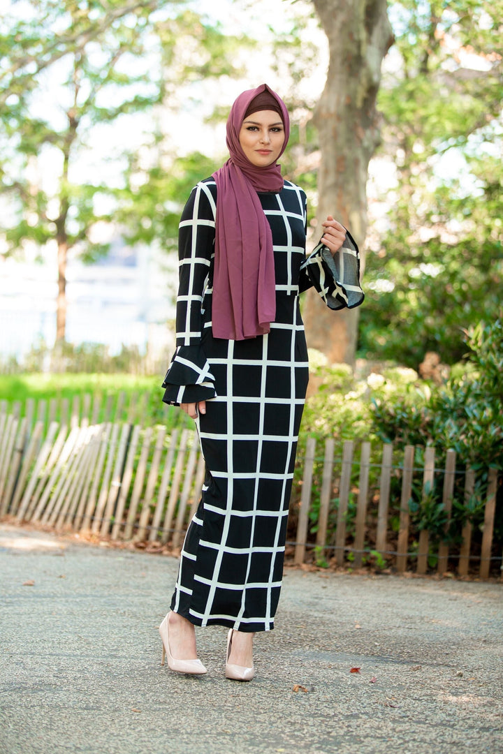 Woman in black and white grid dress with maroon hijab and brown criss-cross underscarf